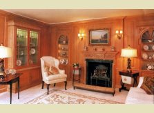 A stained and waxed Hallidays panelled drawing room with display alcoves, hand carved mantlepiece and glazed cabinet.